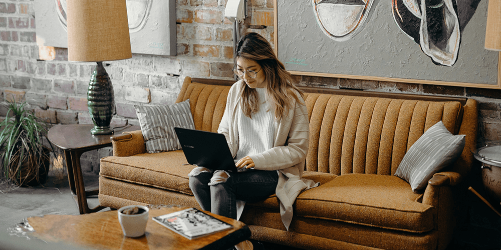 Woman sitting on a sofa with laptop on lap