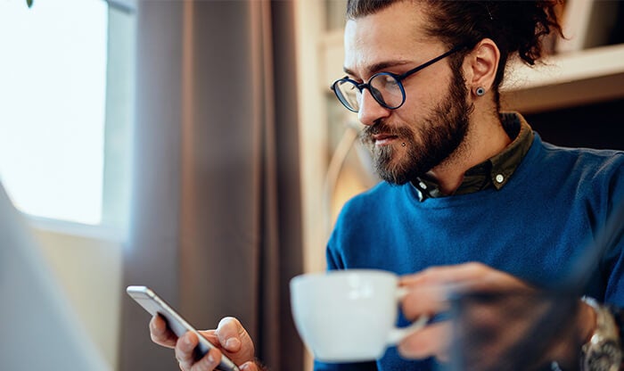 Man drinking coffee and checking his mobile device