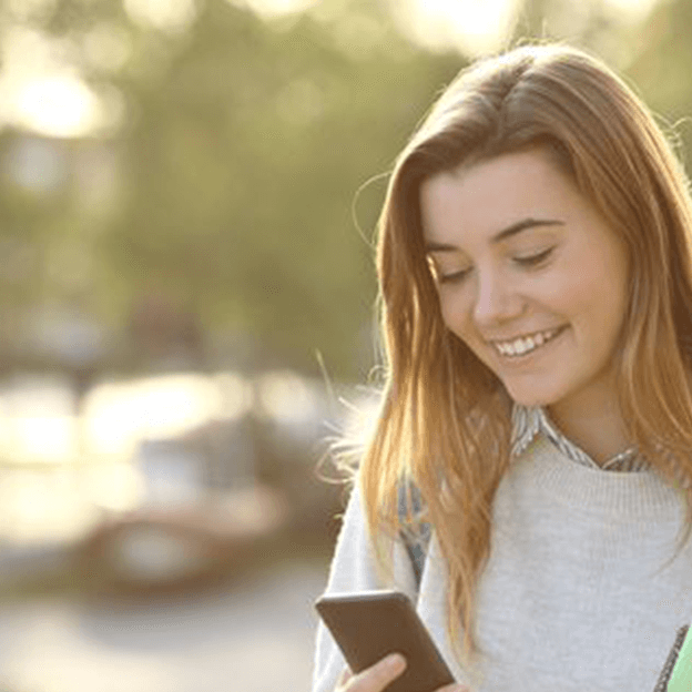College student smiling and texting from her mobile phone