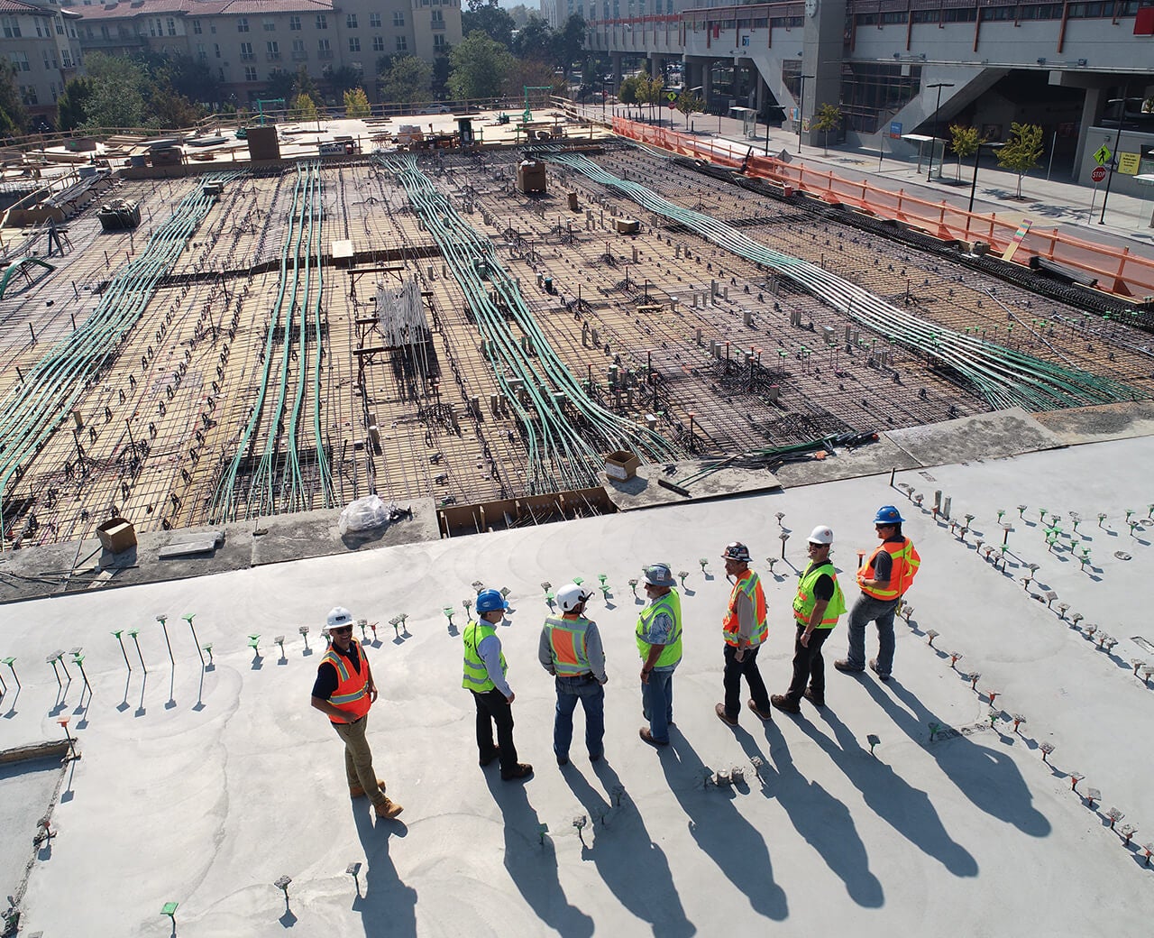Outdoor photo of a large construction site with 7 OHL workers in the foreground