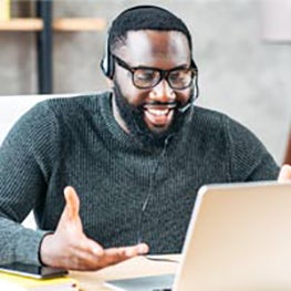 A recruiter happily works at his computer while wearing headphones