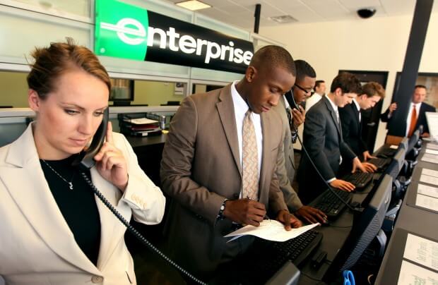 A row of Enterprise rental car personnel working at the front desk