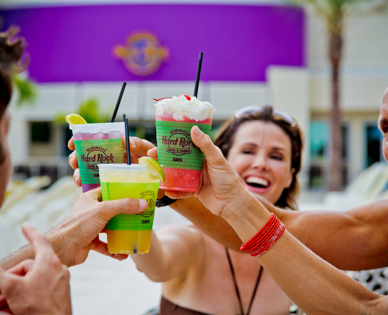A group of people in an outdoor setting clinking their Hard Rock Hotel & Casino branded drinks