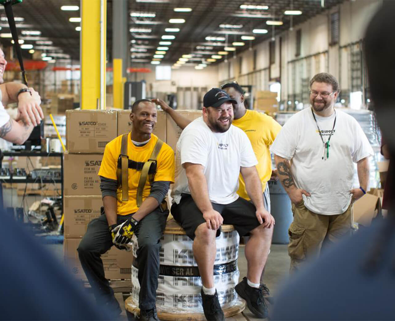 A group of HD Supply personnel laughing and smiling in a warehouse setting