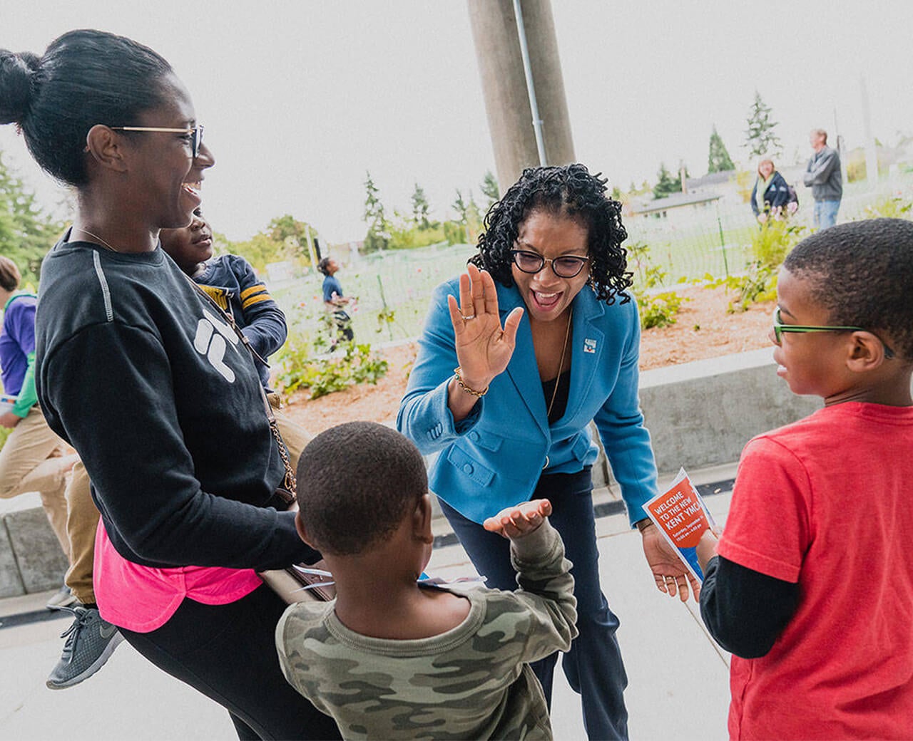 YMCA employee high fives young child at an outdoor event