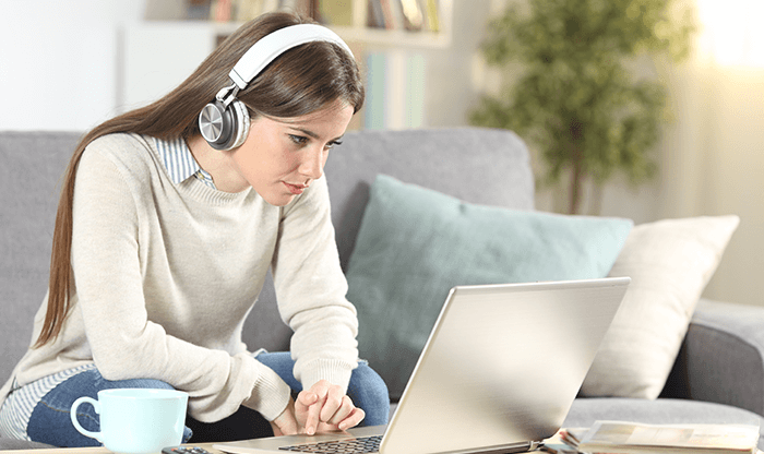 girl with headphones sitting on couch at laptop