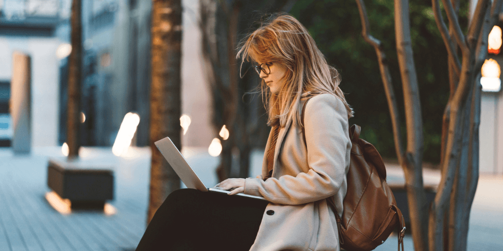 Woman sits on a bench with her laptop