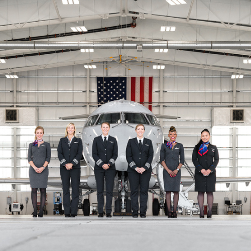 Female employees of PSA Airlines stand in front of a plane in a hanger