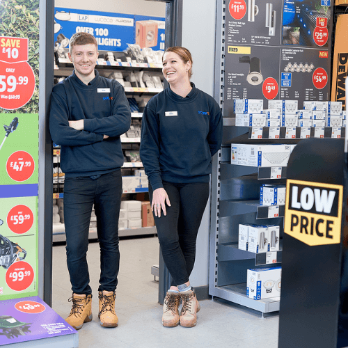 Screwfix employees stand next to a floor display