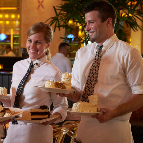 The Cheesecake Factory Employees carry plates of cheesecake