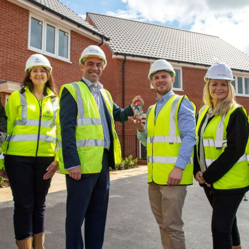 Vistry Group employees wear yellow high-visibility vests outside a newly completed home